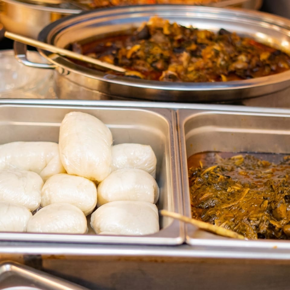 Buffet display featuring steamed buns and two pans of richly sauced savory dishes.